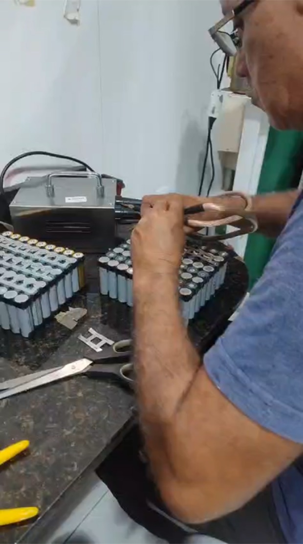Técnico da Teckno Hospitalar soldando um pack de baterias 18650 na bancada, em Belém